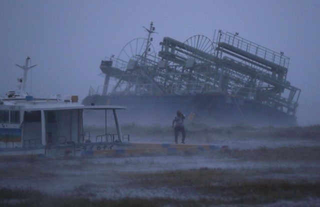 Click to enlarge A person reacts to the weather as ship washed ashore caused by Typhoon Trami is seen at a port in Yonabaru, on the southern island of Okinawa, Japan, in this photo taken by Kyodo September 29, 2018.
