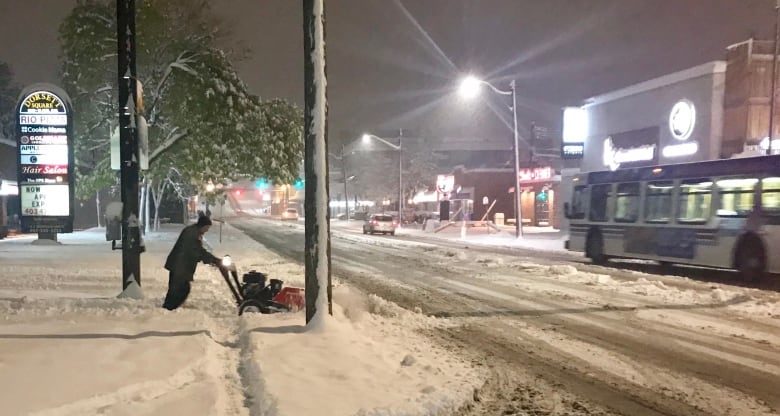 A man clears snow from a section of sidewalk along 14th Street S.W. early Tuesday morning.