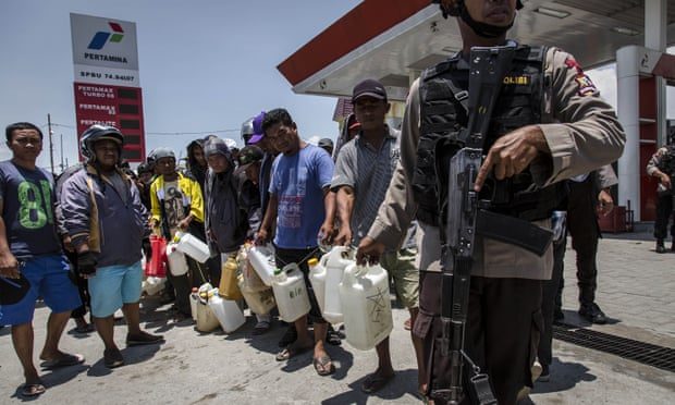 Indonesian police guard a petrol station as people queue for fuel in Palu.