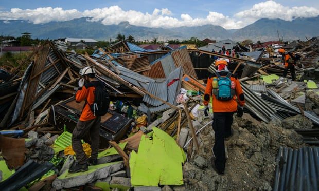 Click to enlarge An Indonesian search and rescue team walk amongst the debris in Petobo, Indonesia