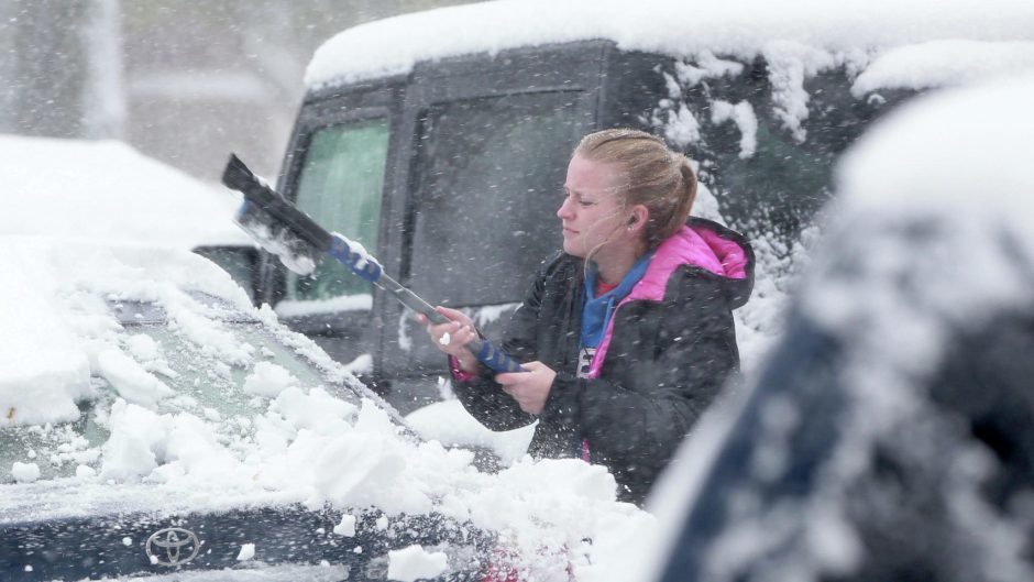 Click to enlarge UND student Kristin Hane clears away snow
