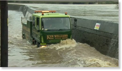 A van drives through the flood water as the River Towy defences at Carmarthen are breached