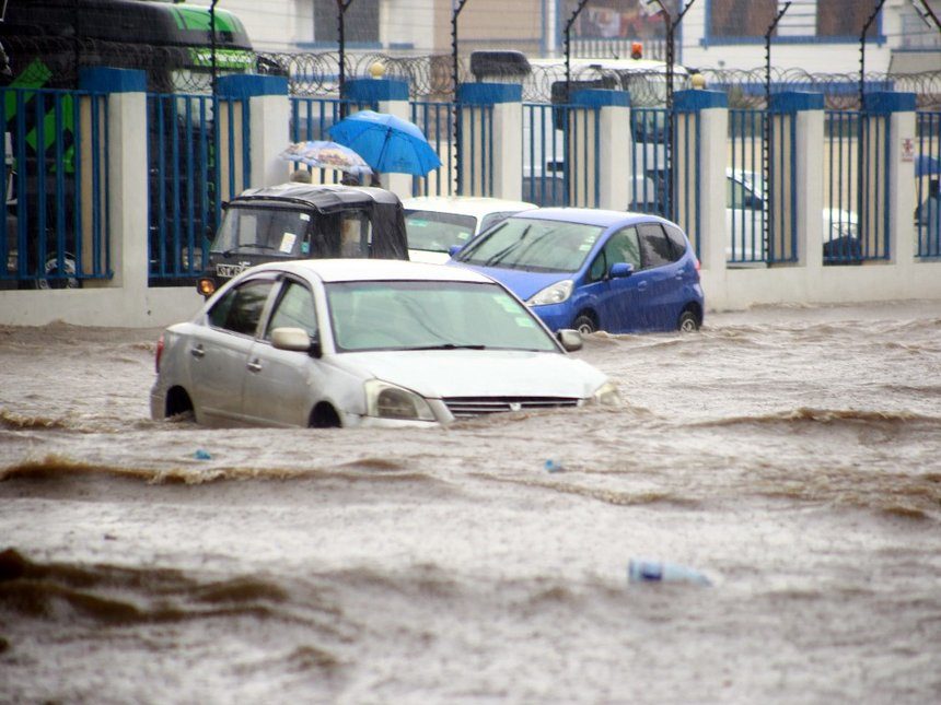 Motorists wade through a flooded road at railways roundabout in Mombasa county yesterday after a heavy downpour.