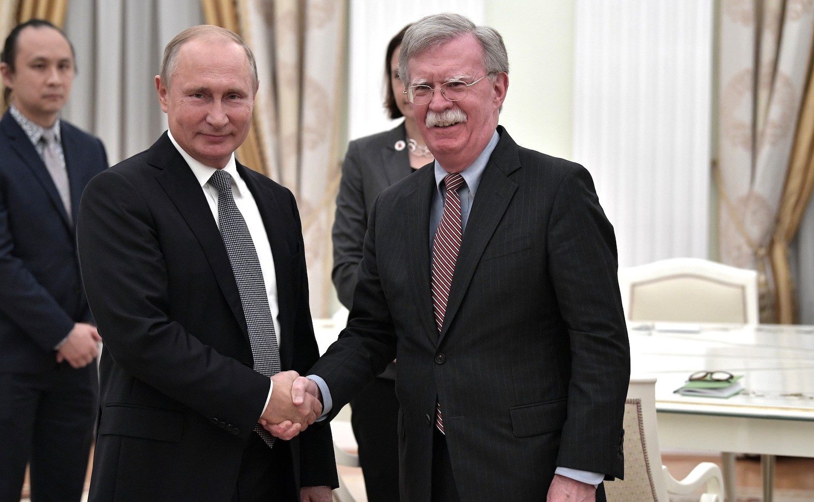 Click to enlarge Russia’s President Vladimir Putin, left, shakes hands with US National Security Adviser John Bolton
