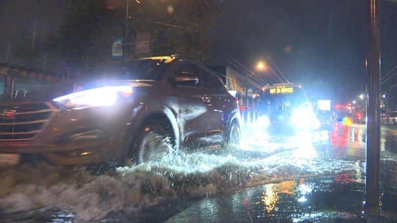 Cars drive through a heavily flooded section