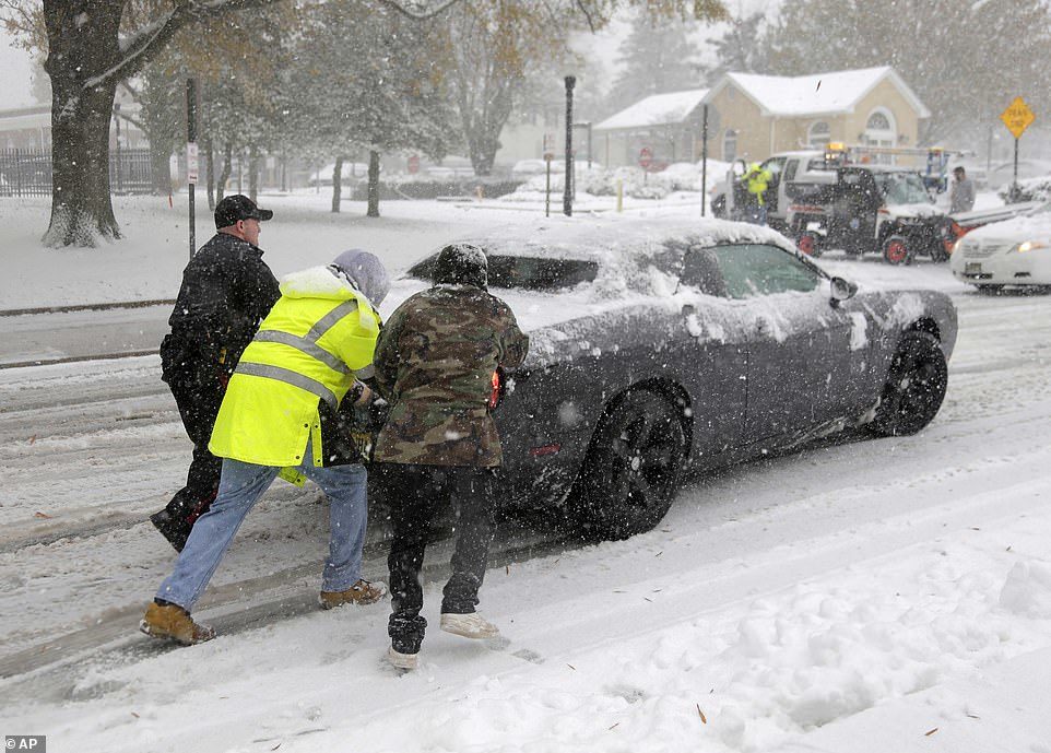 Click to enlarge A police officer and others help push a car t