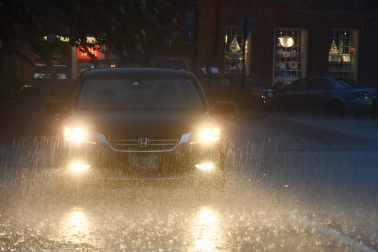 A car drives through the pouring rain on Sunday,