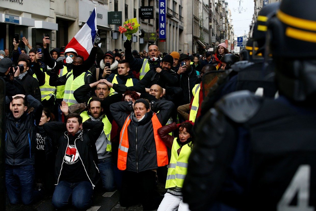 Demonstrators kneel in front of French CRS riot police in Paris