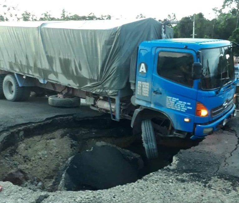 A lorry hangs precariously over the sinkhole