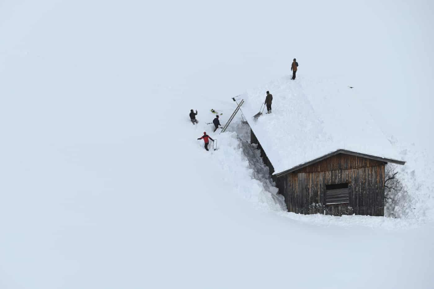 Men clean a roof from snow in Lofer, Austria