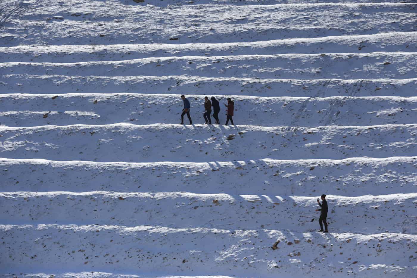 Click to enlarge People walk across the snow after a snowfall in