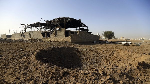 A bomb crater lies beside a factory destroyed in Saturday night's Saudi-led coalition bombing, January 20, 2019