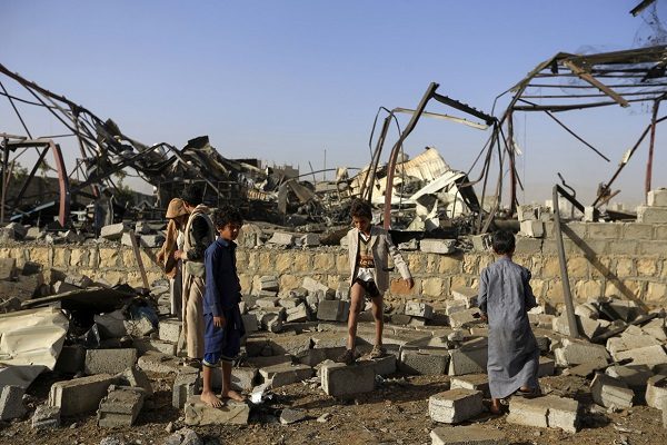 Children search for scrap metal in the ruins of a factory bombed by coalition warplanes overnight, January 20, 2019
