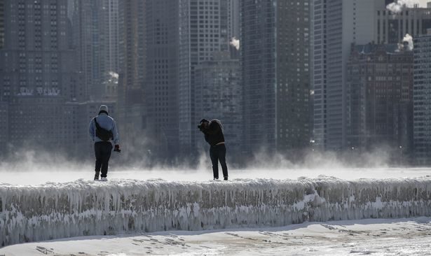 People take pictures as steam rises from the Lake Michigan