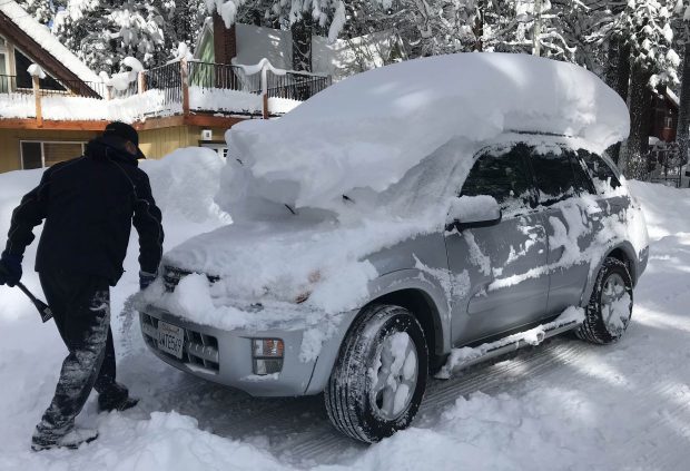 Click to enlarge A man removes snow from his car after a winter storm this February.