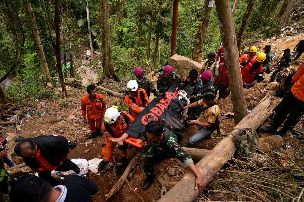 Rescue workers carrying a body bag containing a victim of the landslide at an illegal gold mine in Indonesia last week.