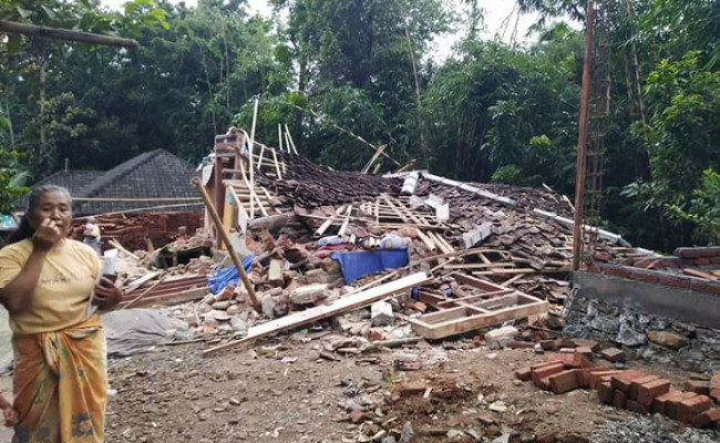Click to enlarge A resident of Montong Gading district, East Lombok, stands by her collapsed house after an earthquake on Sunday
