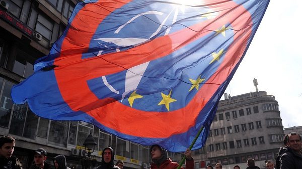 An anti-NATO protester man waves a flag in downtown Belgrade