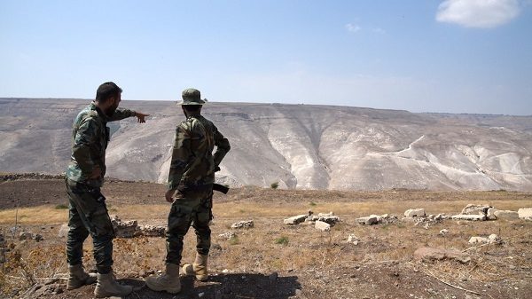 Syrian soldiers look at the Israeli-controlled Golan Heights near Daraa, Syria. August 2018