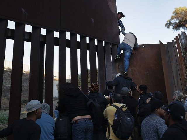 migrants climb border wall