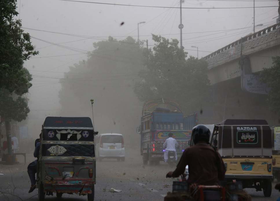Vehicles commute during the dust storm in Karachi
