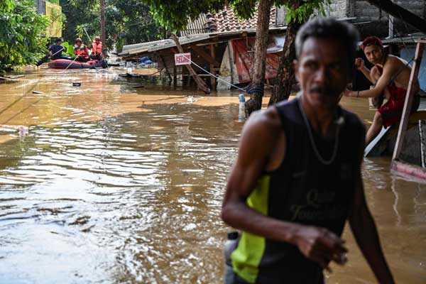 A resident walks through floodwaters in Jakarta