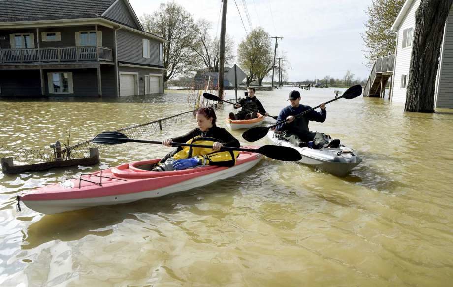 In this Wednesday, May 8, 2019 photo, Estral Beach Firefighters Courtney Millar, Eric Bruley, and Chase Baldwin kayak down Lakeshore Dr.