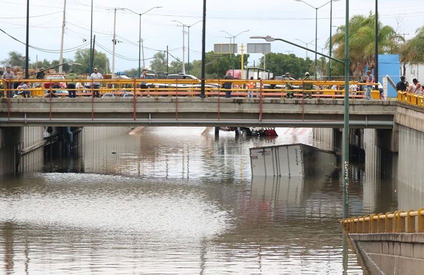 A truck is almost completely submerged below an overpass in León.