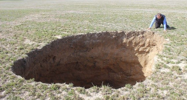 A man looks at a 10-meter-deep sinkhole