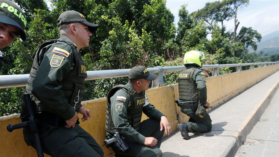 Click to enlarge Police officers take cover as shots are fired near the Simon Bolivar international bridge