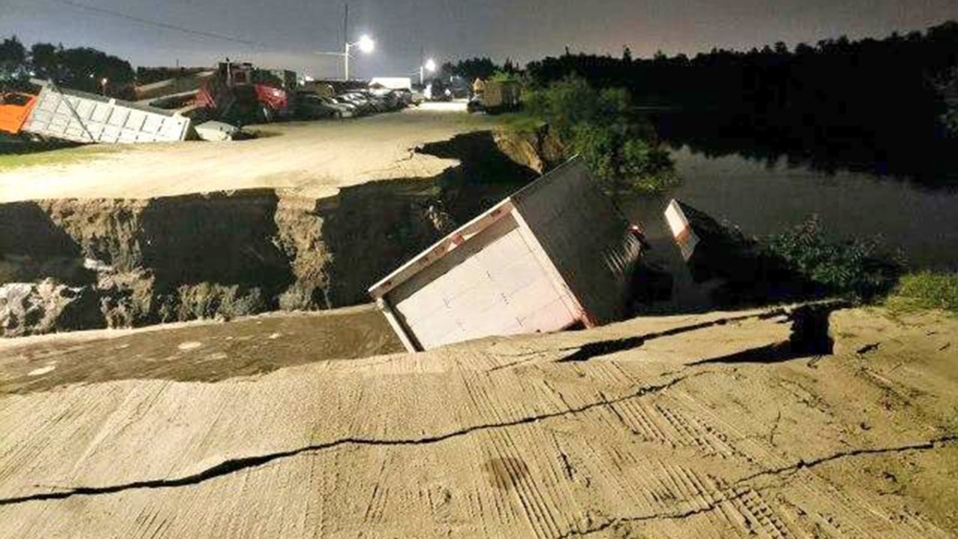 Officials are investigating if the trucks fell into a sinkhole or if the fracture in the ground was caused by something else.