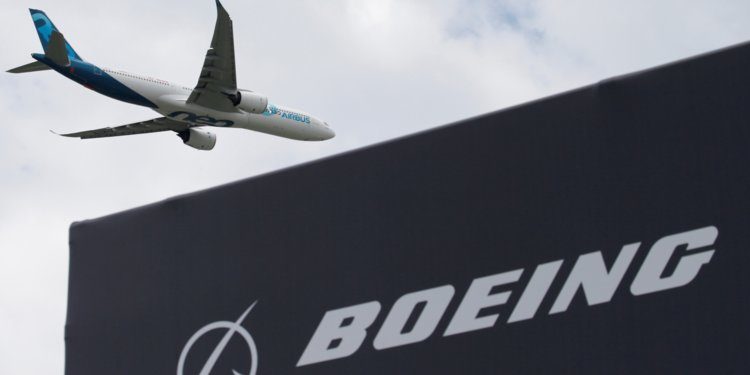 An Airbus A330neo flying past a Boeing sign at the 2019 International Paris Air Show.