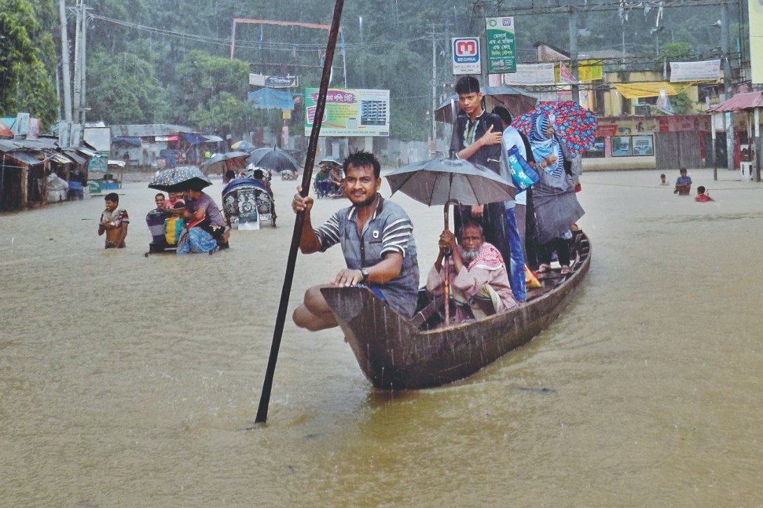 A man rows a boat on a flooded street in Bandarban Bus Station area in the pouring rain yesterday. The Sangu burst its bank near the town inundating several neighbourhoods.