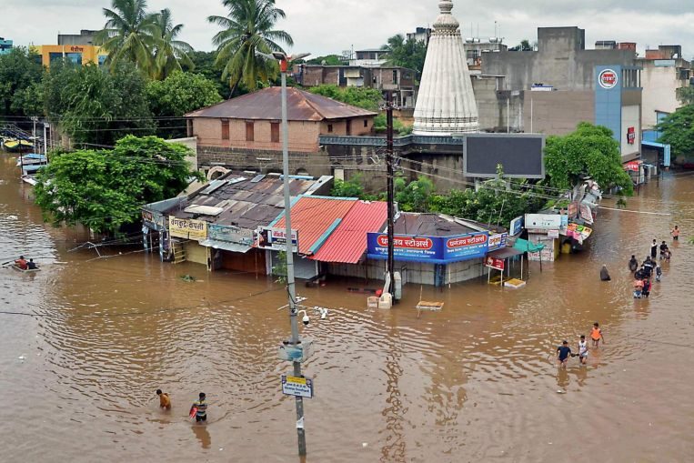 In this picture taken on Aug 6, 2019 people wade through a flooded street in Sangli, Maharashtra. The tally of dead in the floods was 25 in the western state of Maharashtra.