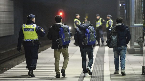Click to enlarge Police officer escorts migrants