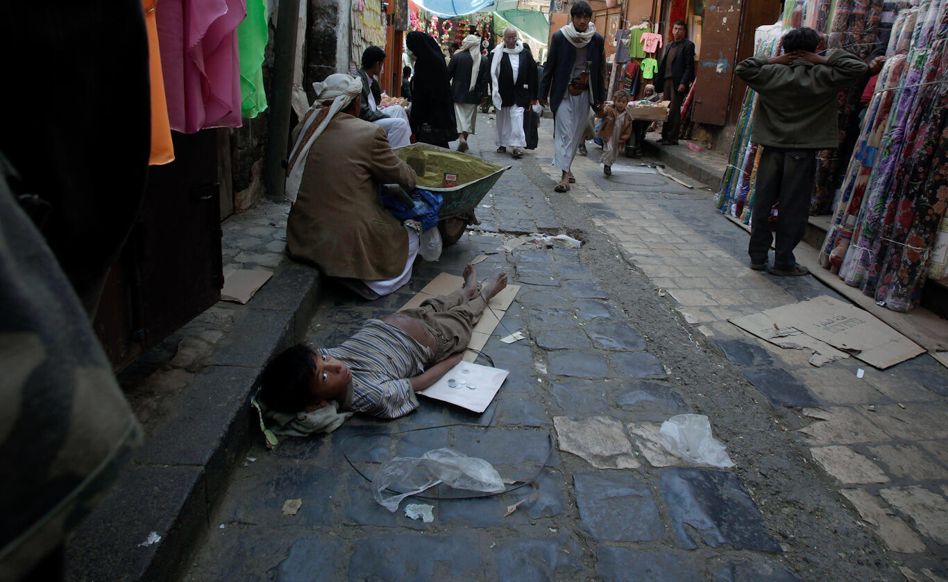 A Yemeni boy looks back while laying on the ground as he begs for money in an alley of the old city of Sanaa, Yemen.