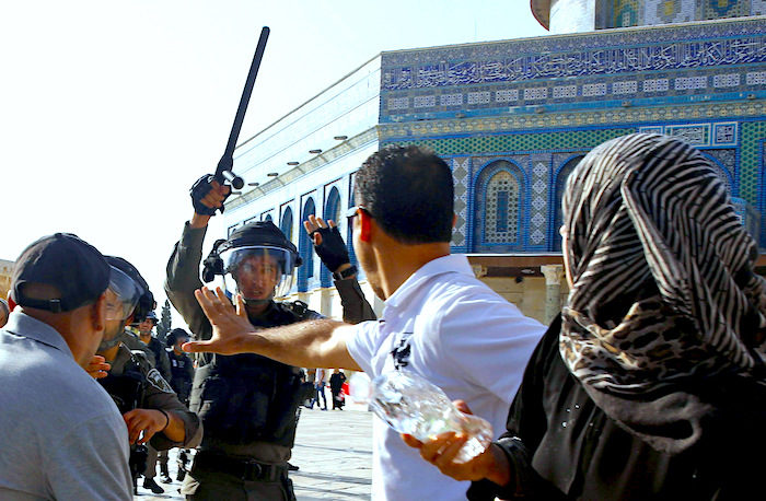 Click to enlarge An Israeli police officer raises his baton