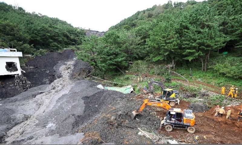 Click to enlarge Rescue teams search for four people believed to be trapped after a landslide buried a house and restaurant in Busan