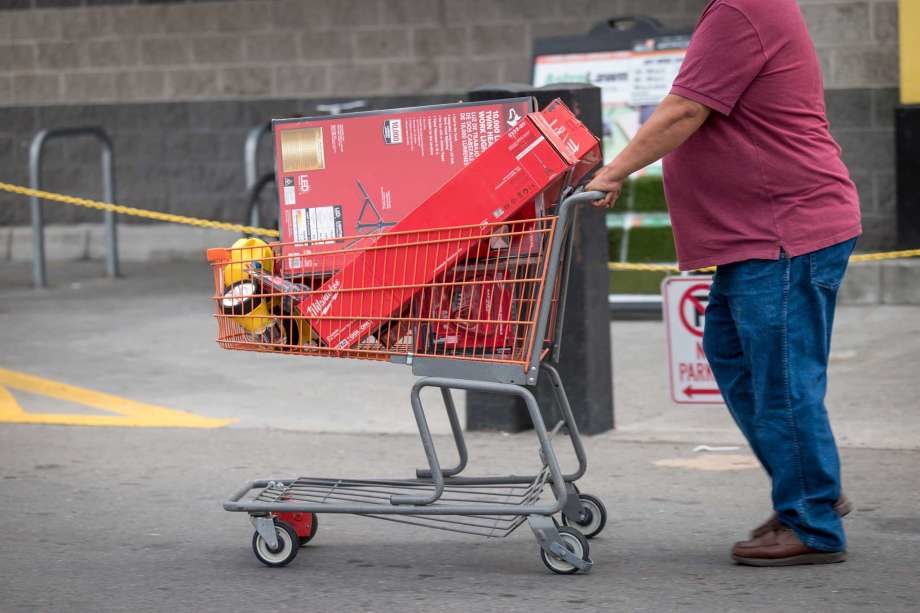 A customer pushes a shopping cart with batteries and flashlights