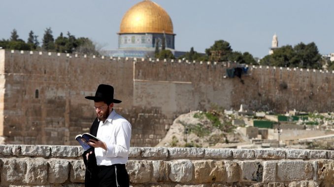 Click to enlarge Ultra Orthodox Jew walks reading from a book