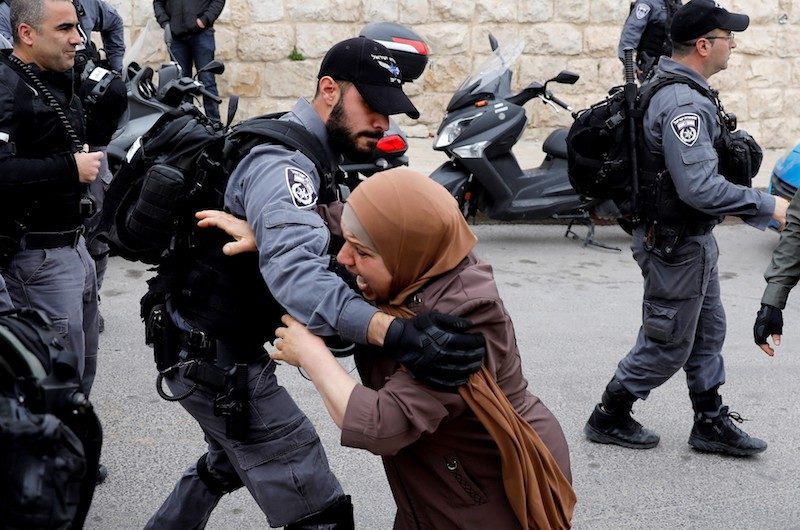 Click to enlarge An Israeli policeman pushes back a Palestinian woman