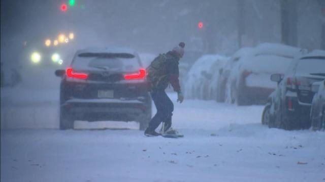 Click to enlarge A person tries to ride a snowboard down the road in Denver Wednesday morning.
