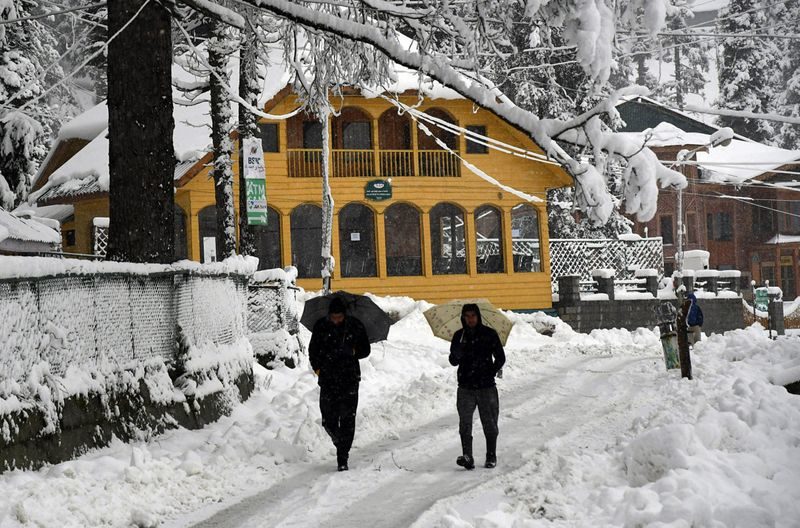 Click to enlarge People walk on a snow-covered road during the first snowfall of the season in Gulmarg. Kashmir witnessed its first snowfall of the season, plunging the mercury to sub-zero in Gulmarg and bringing woes galore.