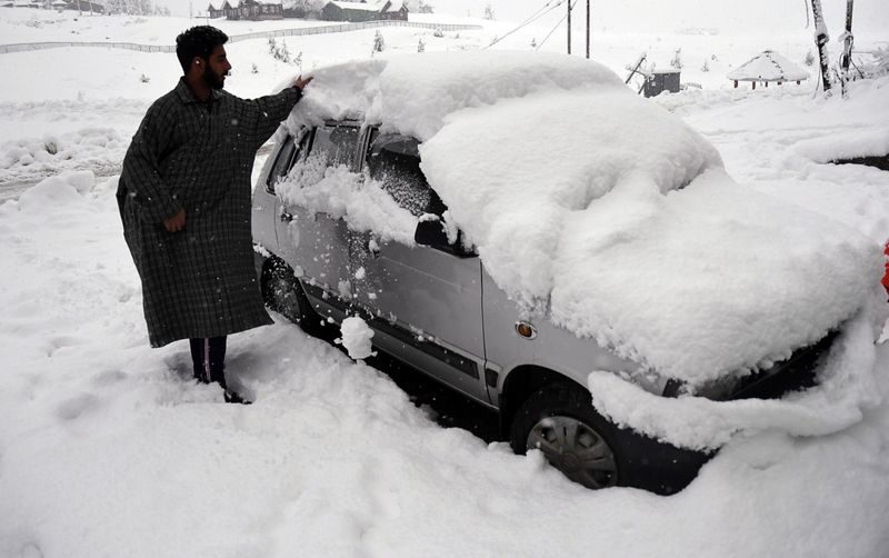 Click to enlarge A man removing snow from a car during the first snowfall of the season in Gulmarg. While the snowfall has been moderate in the plains of Kashmir, the upper reaches have witnessed heavy snowfall.