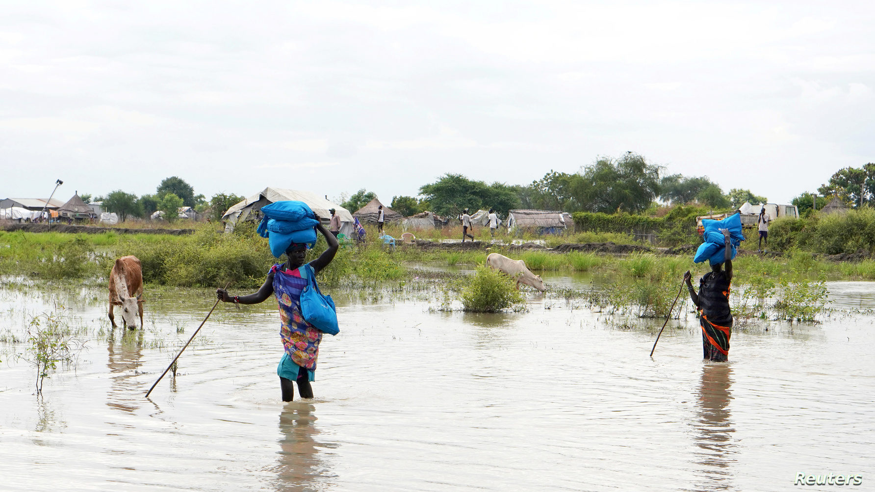 Women carry belongings on their heads as they wade through water, after heavy rains and floods forced hundreds of thousands of people to leave their homes, in the town of Pibor, Boma state, South Sudan, Nov. 6, 2019.