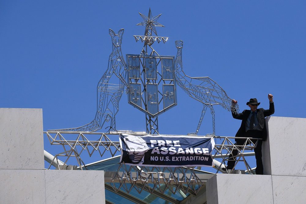Click to enlarge protester scales parliament assange