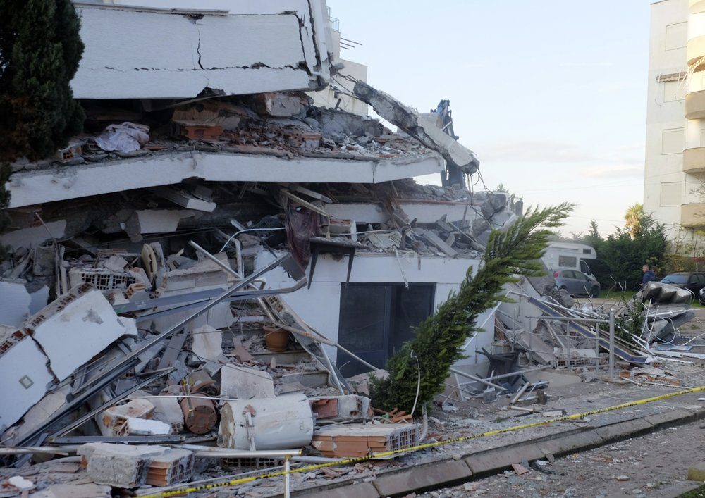 A man passes next to a damaged building after a magnitude 6.4 earthquake in Durres, western Albania, Tuesday, Nov. 26, 2019.