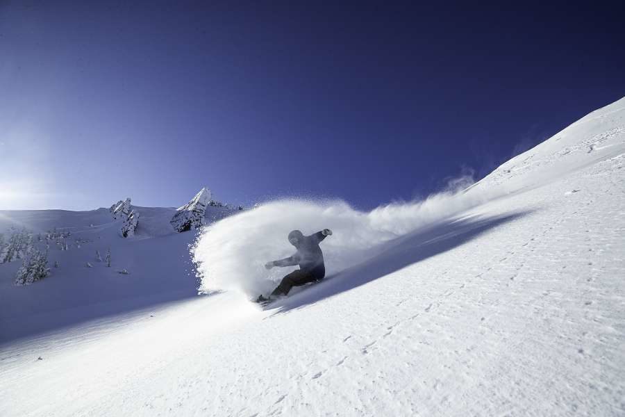 A snowboarder shreds on a virgin slope on a bluebird day out of Alpine Meadows at Lake Tahoe