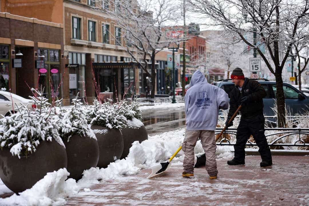 Landscape workers shovel snow from the walk paths downtown on Dec. 29, 2019, in Sioux Fall