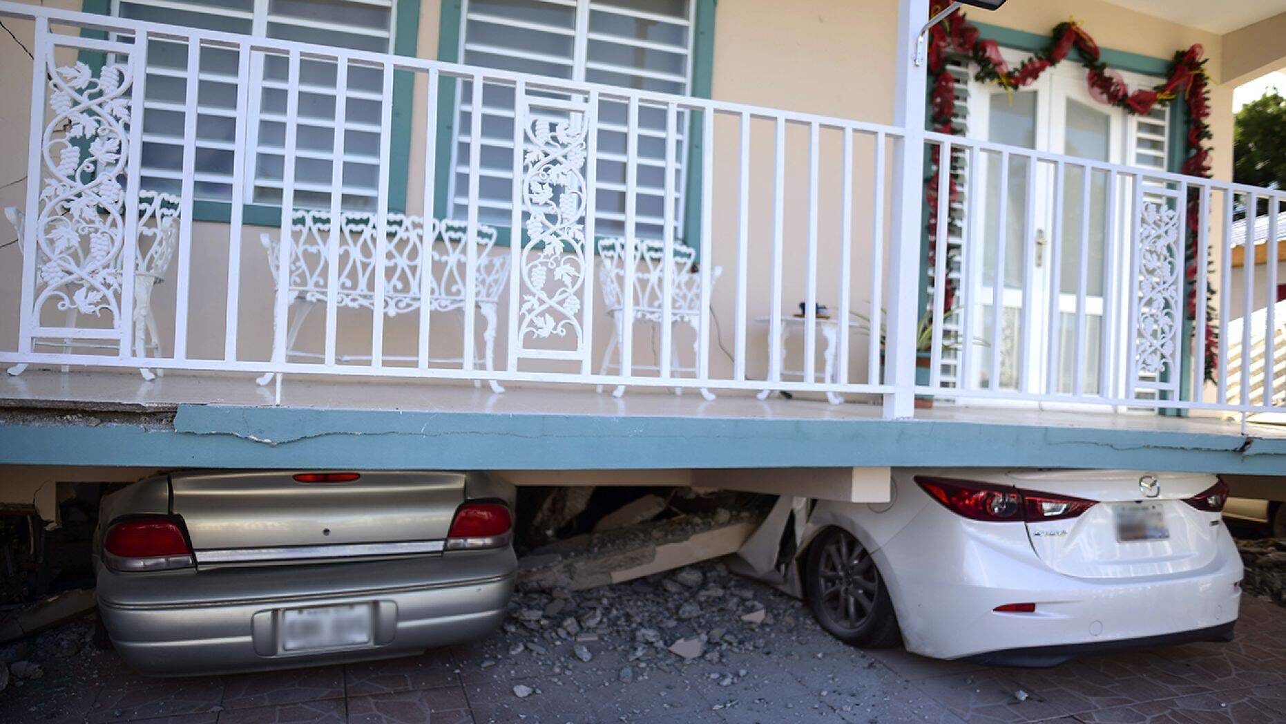 Cars were crushed under a home in Guanica that collapsed after Monday's earthquake